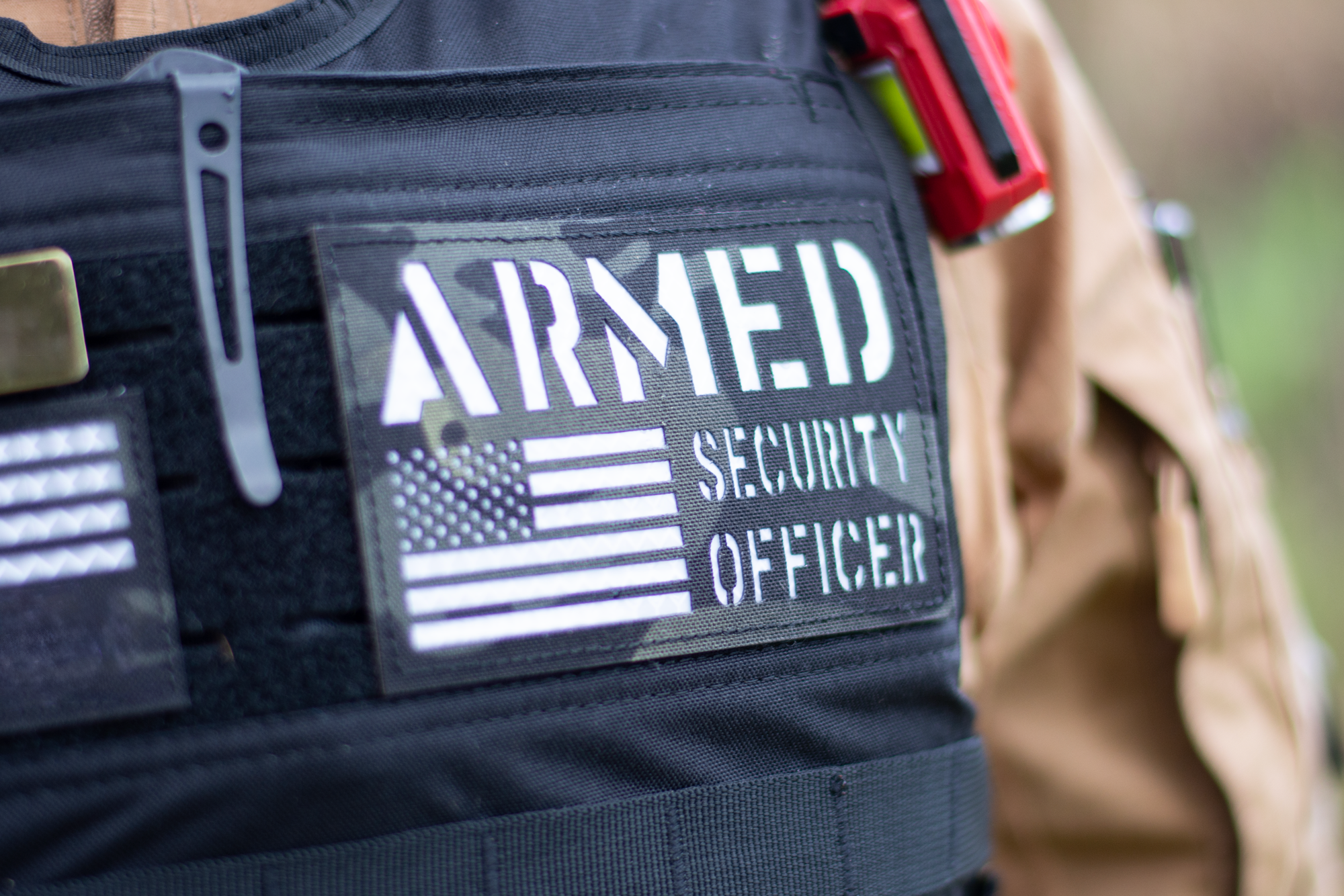 A man in a vest labeled 'Armed Security Officer' stands confidently, representing Alpha Security Academy's training program.